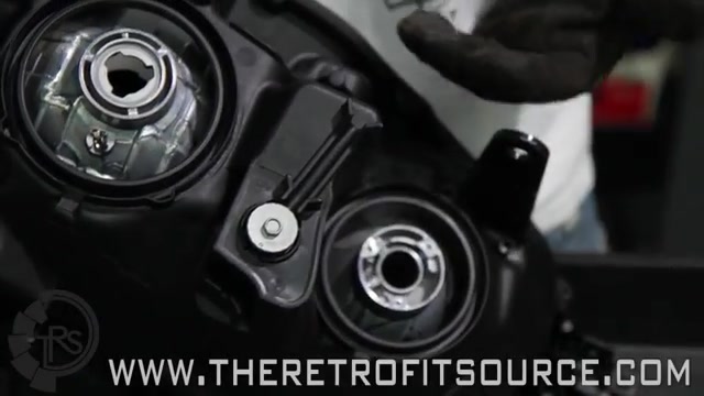 Backing out the aiming adjuster screw on a headlight reflector